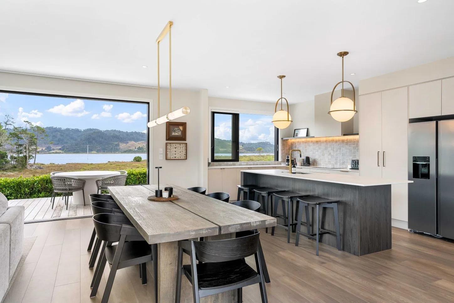Open-plan kitchen and dining table with pendant lights and a water view
